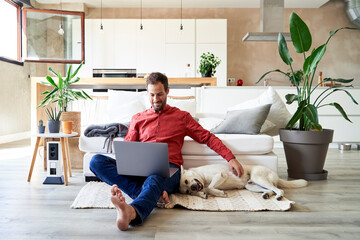 Freelancer sitting with laptop and petting his dog