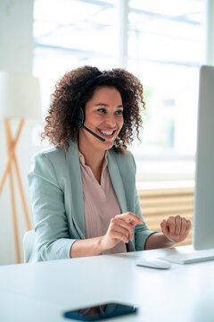 Happy customer service representative discussing through headset at workplace