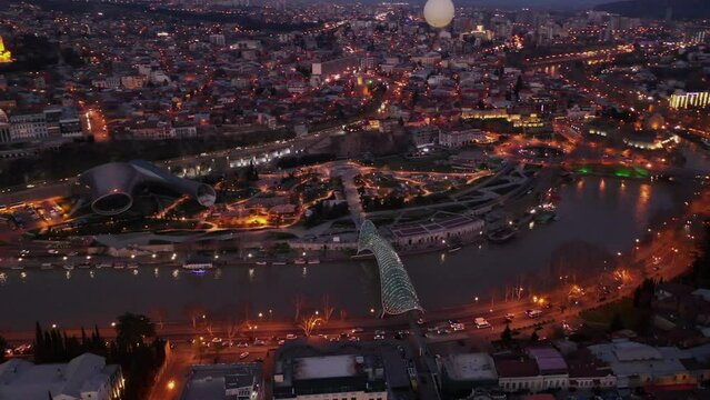 Scenic aerial view of historical area of Tbilisi on banks of Kura river and surroundings in evening lights in spring, Georgia