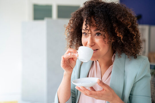 Mature businesswoman drinking coffee in break time at workplace
