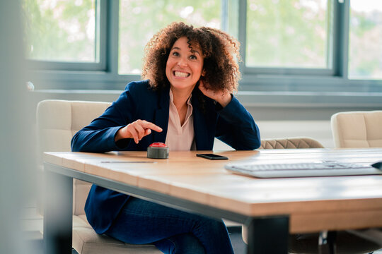 Cheerful businesswoman with buzzer button in board room