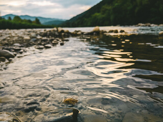 Beautiful cloudy sky at sunset over the river. The high bank of the river is overgrown with grass.