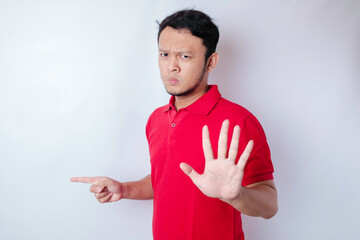 Attractive Asian man with hand gesture pose rejection or prohibition while pointing to copy space...