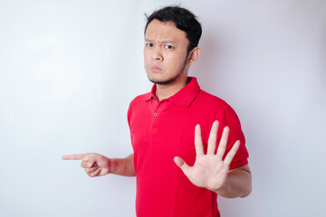 Attractive Asian man with hand gesture pose rejection or prohibition while pointing to copy space...