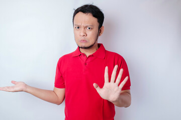 Attractive Asian man with hand gesture pose rejection or prohibition while pointing to copy space...