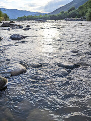 Beautiful cloudy sky at sunset over the river. The high bank of the river is overgrown with grass.