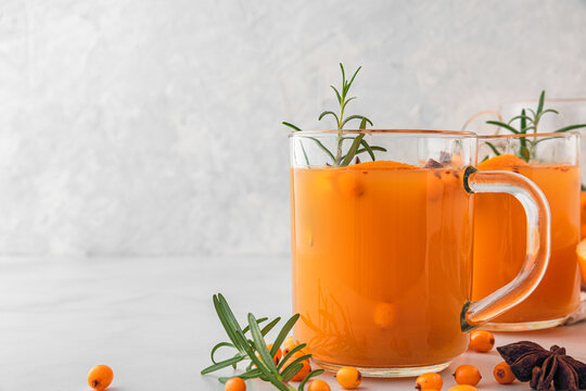 Autumn drink. Sea buckthorn tea with orange, cinnamon and rosemary in glasses on white background