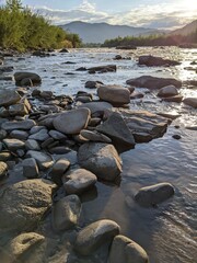 Beautiful cloudy sky at sunset over the river. The high bank of the river is overgrown with grass.