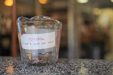 Glass jars filled with dollar coins, savings inside glass jar, money isolated on blur background. Paper note written funny note. Tipping jar.