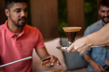 Smiling afro man at coffee break paying with credit card
