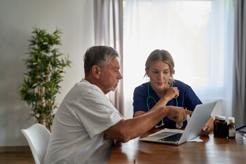 Caucasian female doctor analyzing medical tests with senior patient at home visit