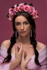 A wreath of pink roses is a beautiful headdress for a girl. Portrait of an attractive young Ukrainian woman in a wreath with clean skin. Concept wedding style or beauty salon and skin care.