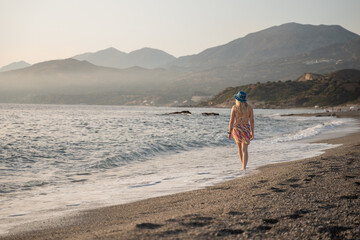 young woman walking into the sunset on a beach on the Greek island of Crete. Summer vacation in Crete