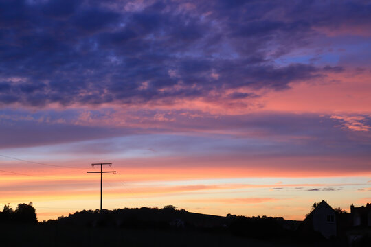 Farbenfroher Sonnenuntergang mit Silhouette einer Landschaft mit Strommast