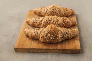 Three wholemeal croissants with bran on a gray background