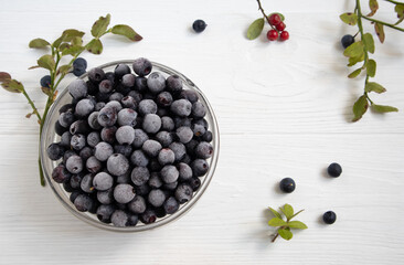 Frozen blueberries in a glass bowl, highlighted on a white background with a space to copy.
