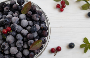 Frozen blueberries in a glass bowl, highlighted on a white background with a space to copy.