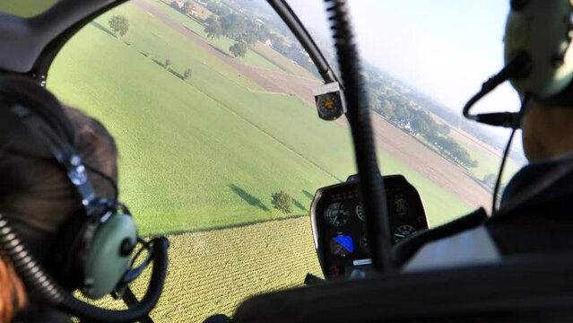 Inside helicopter cockpit during turn over green fields