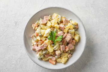 Traditional Russian or Ukrainian salad Olivier from boiled vegetables and sausage with mayo on white table. top view