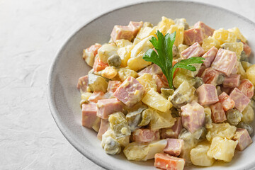 Russian Christmas or New Year salad Olivier from boiled vegetables and sausage with mayo on white table