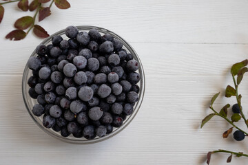 Frozen blueberries in a glass bowl, highlighted on a white background with a space to copy.