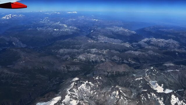 Passenger point of view of flying Easyjet airplane wing in blue sky over French Alps mountains