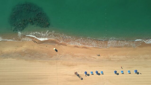 Aerial shot over a beach of yellow sand and transparent turquoise water in Malgrat de Mar, province of Barcelona Flight over hammocks and deckchairs