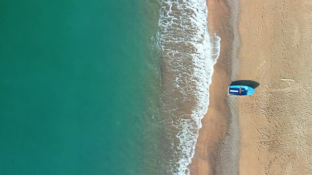 Overhead aerial image of a beach with a small fishing boat static shot