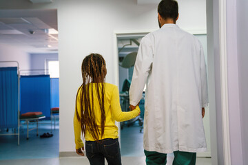 Doctor having conversation with sad little girl at the hospital. Doctor consoling child