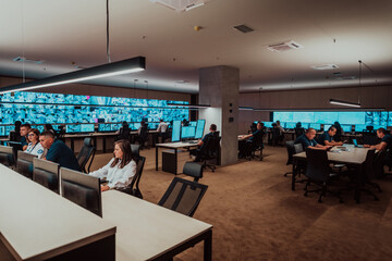 Group of Security data center operators working in a CCTV monitoring room looking on multiple monitors Officers Monitoring Multiple Screens for Suspicious Activities Team working on the System Contr