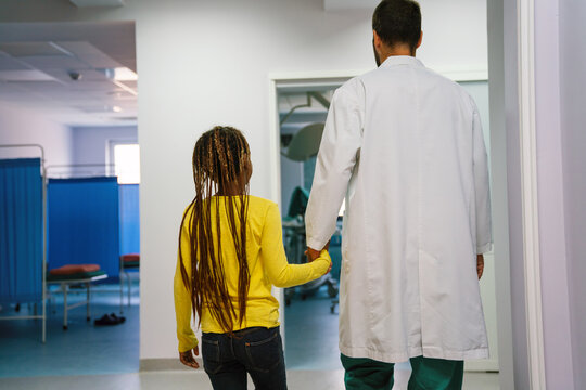 Doctor Having Conversation With Sad Little Girl At The Hospital. Doctor Consoling Child