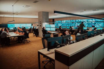 Group of Security data center operators working in a CCTV monitoring room looking on multiple monitors Officers Monitoring Multiple Screens for Suspicious Activities Team working on the System Contr