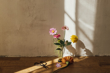 Autumn still life. Autumn flowers composition and scissors in sunny light in modern rustic room