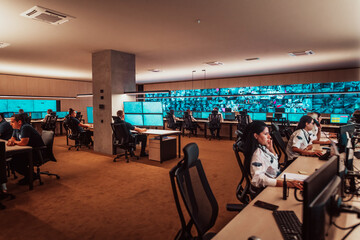 Group of Security data center operators working in a CCTV monitoring room looking on multiple monitors Officers Monitoring Multiple Screens for Suspicious Activities Team working on the System Contr