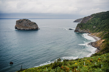 Rocky coast with blue ocean, rocks and mountain in the Cantabrian Sea, Basque Country, Spain