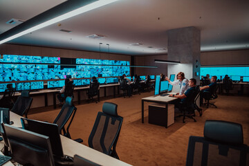Group of Security data center operators working in a CCTV monitoring room looking on multiple monitors Officers Monitoring Multiple Screens for Suspicious Activities Team working on the System Contr
