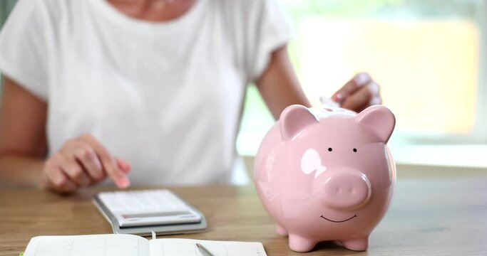 Female hand inserting electronic plug into piggy bank closeup 4k movie slow motion