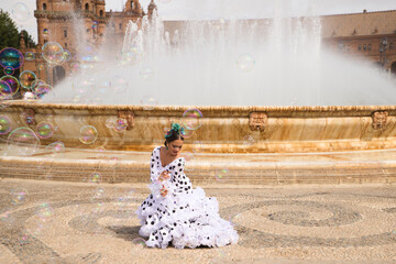Flamenco dancer woman, teenage brunette and beautiful typical Spanish dancer is dancing between soap bubbles in front of a fountain. Flamenco concept of the cultural heritage of humanity - obrazy, fototapety, plakaty