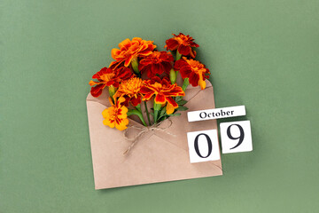 October 9. Bouquet of orange flower in craft envelope and calendar date on green background. Minimal concept Hello fall. Template for your design, greeting card
