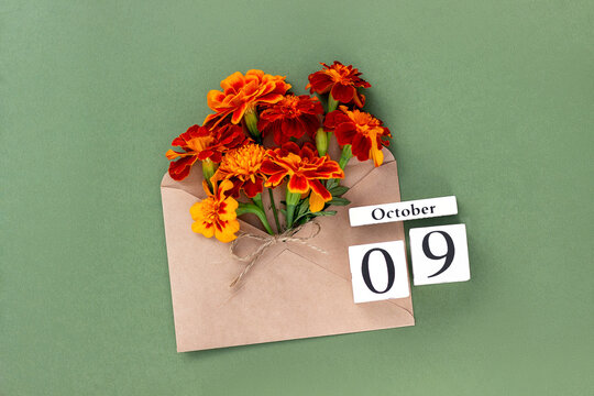 October 9. Bouquet of orange flower in craft envelope and calendar date on green background. Minimal concept Hello fall. Template for your design, greeting card