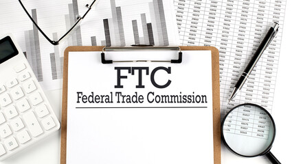 Paper with FTC -FEDERAL TRADE COMMISSION on a chart with calculator,pen and magnifier - obrazy, fototapety, plakaty