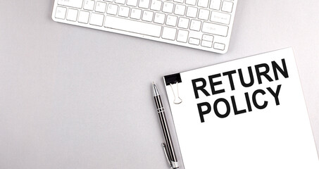 RETURN POLICY text on paper with keyboard on grey background