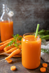 Fresh natural juice, healthy food concept. Glass jar of fresh carrot juice with fresh carrots on a rustic table. Copy space.