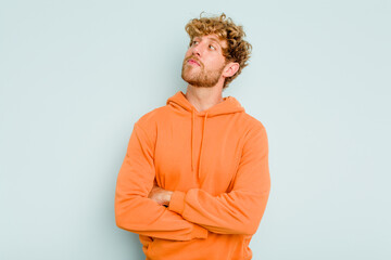 Young caucasian man isolated on blue background dreaming of achieving goals and purposes