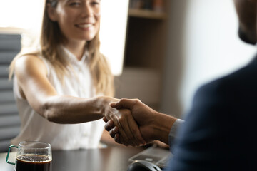 Close up of two business man shaking hands, while sitting by the office table