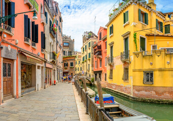 View on the narrow cozy streets of the canals with parked boats in Venice, Italy. Architecture and landmark of Venice.