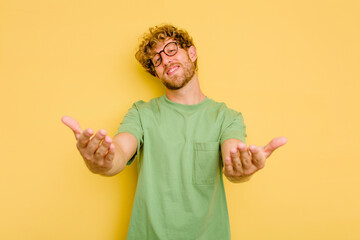 Young caucasian man isolated on yellow background showing a welcome expression.