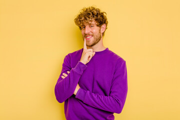 Young caucasian man isolated on yellow background smiling happy and confident, touching chin with hand.