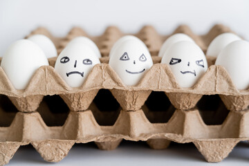 Painted eggs with different facial expressions in carton boxes on white background.