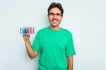 Young hispanic man holding battery box isolated on white background happy, smiling and cheerful.